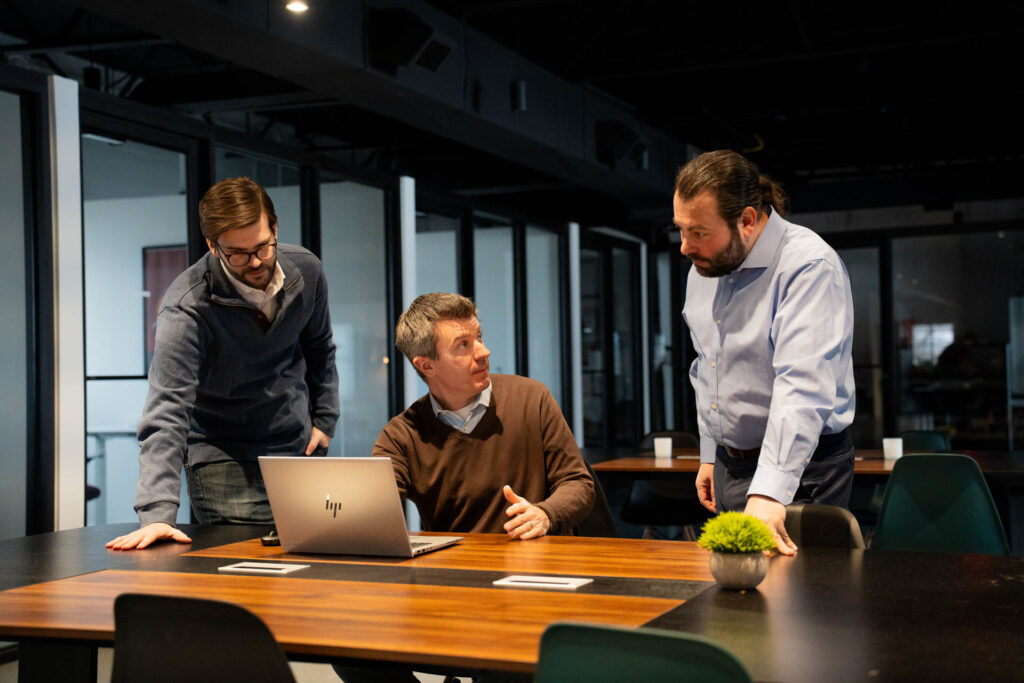 InnerView Group professionals collaborating around a laptop in a modern office meeting space.