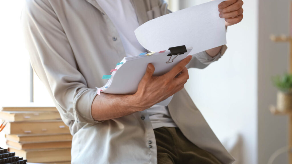 Person reviewing printed documents with tabs, evaluating or editing content.