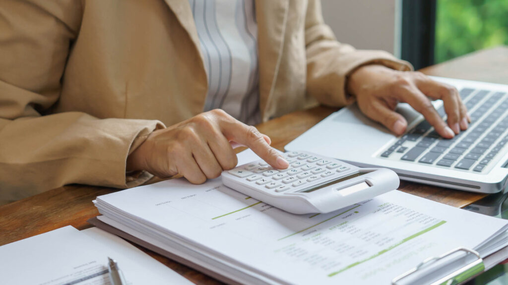Professional reviewing paperwork and using a calculator to analyze business data.