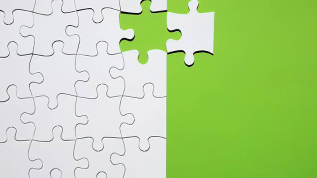 Puzzle pieces coming together with one highlighted green piece symbolizing alignment and strategy.