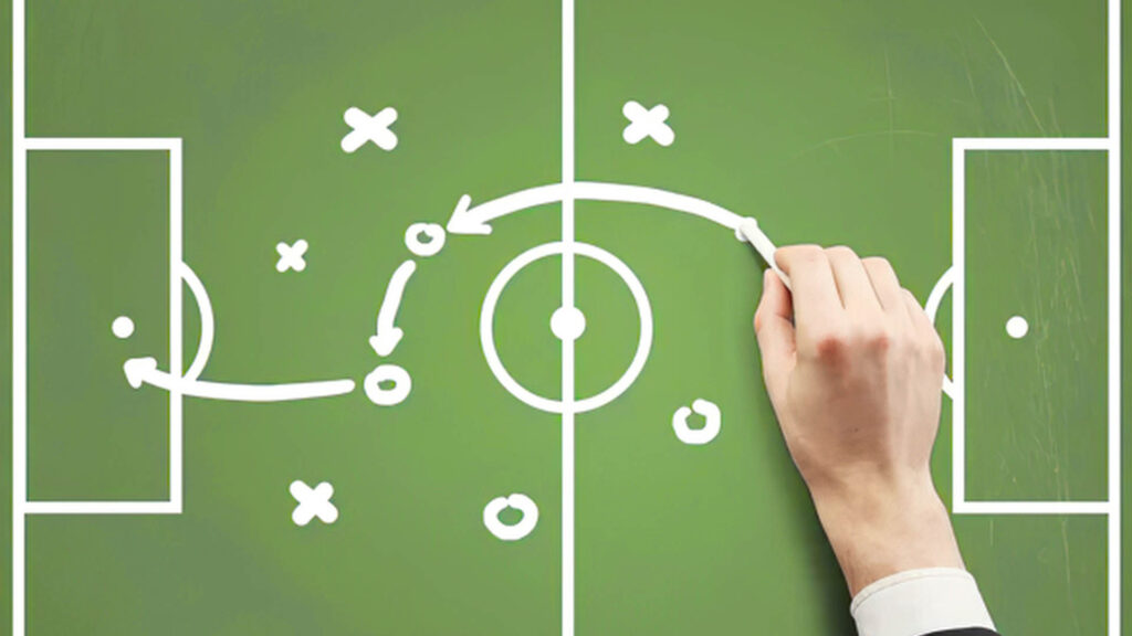 Hand drawing strategy plays on a soccer field diagram, representing leadership and planning.