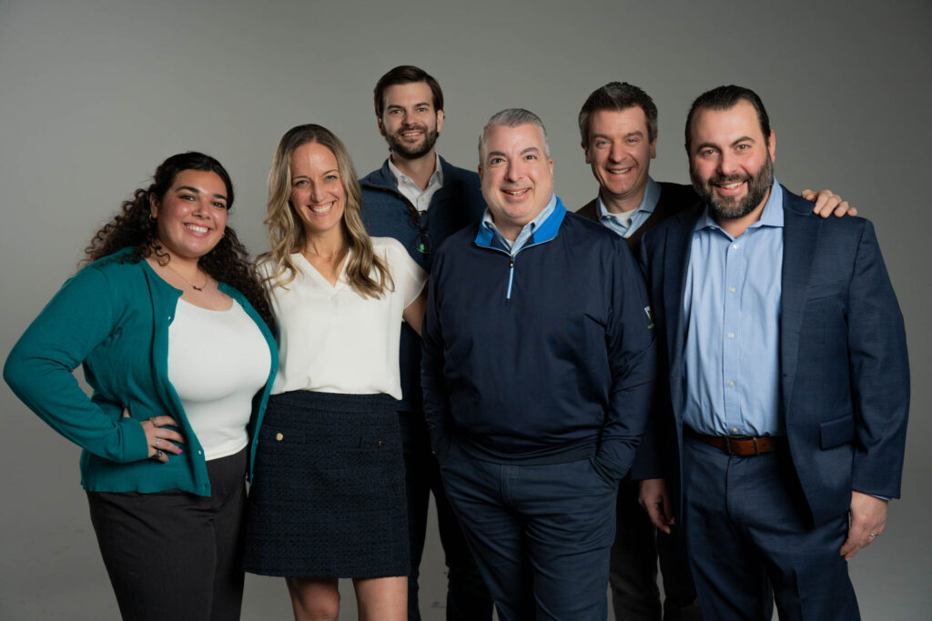 team members standing together and smiling in a studio portrait