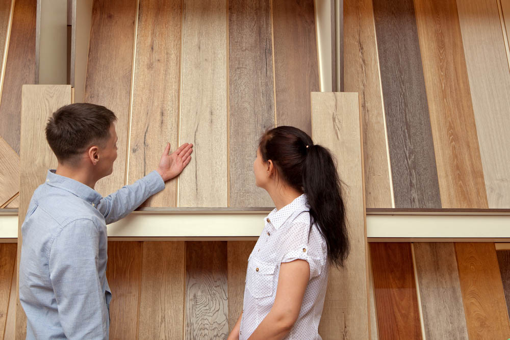 Couple examining different flooring options displayed on a wall.
