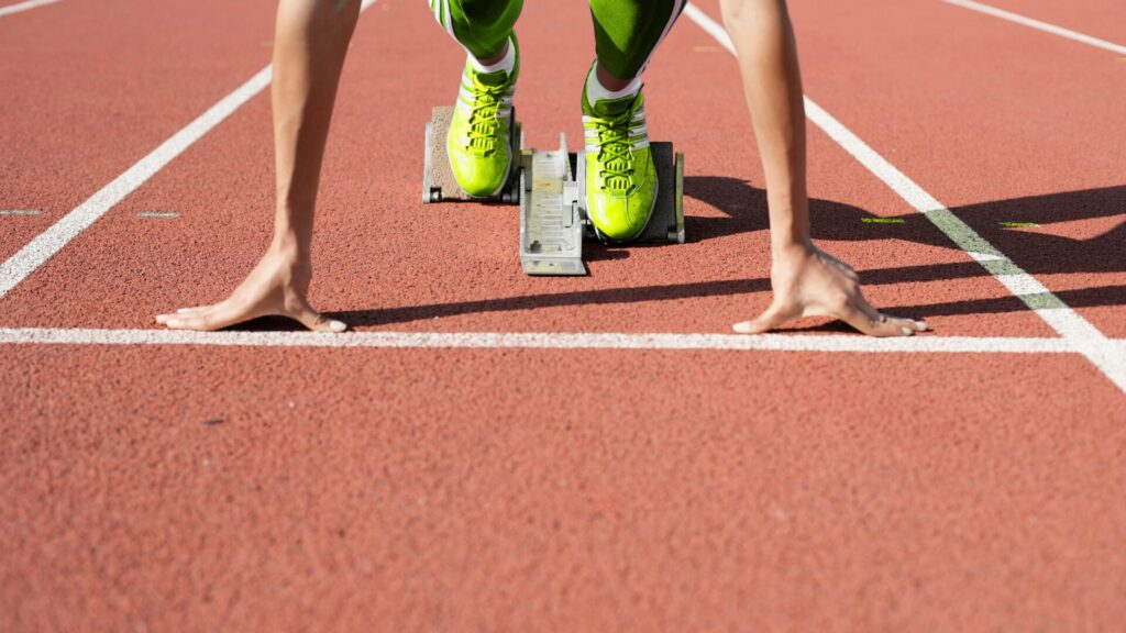 Runner in starting blocks on a track, ready to sprint.